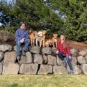 Two people with several dogs outdoors.